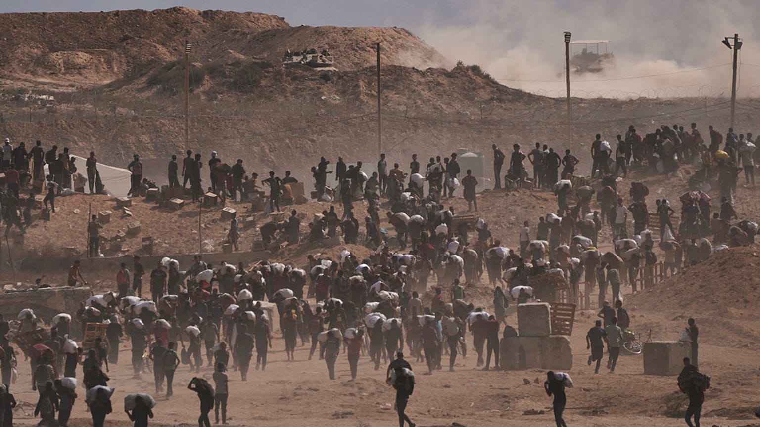فلسطينيون يحملون طرود مساعدات إنسانية بالقرب من مركز توزيع مؤسسة غزة الإنسانية الذي تديره المنظمة المدعومة من الولايات المتحدة، في نتساريم، وسط قطاع غزة