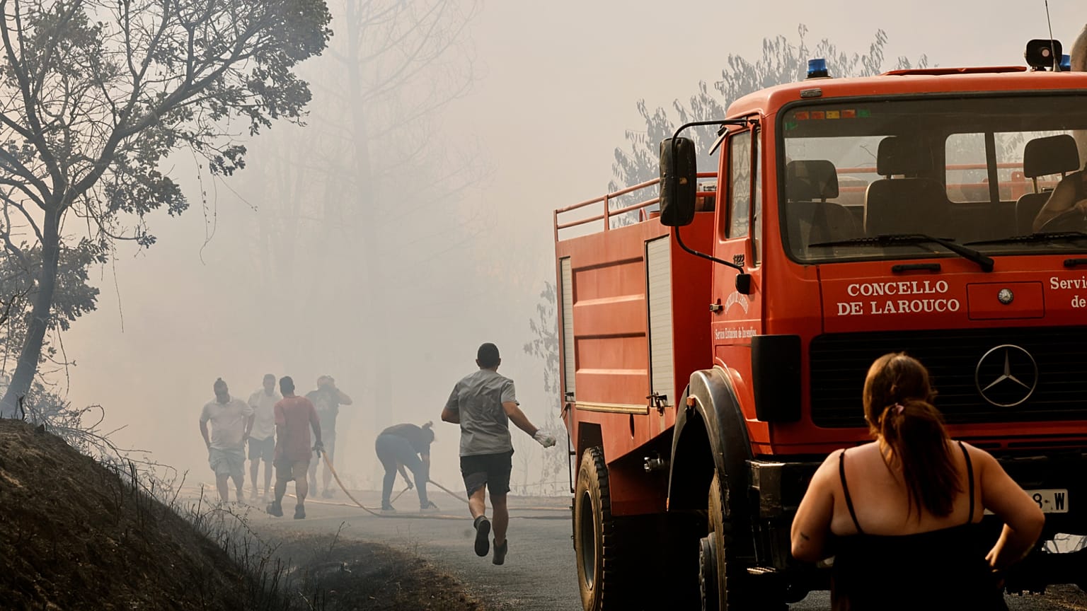 Firefighters and a local residents try to put out a forest fire in Larouco, northwestern Spain, Wednesday, Aug. 13, 2025. 
