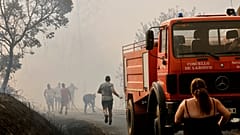 Firefighters and a local residents try to put out a forest fire in Larouco, northwestern Spain, Wednesday, Aug. 13, 2025. 