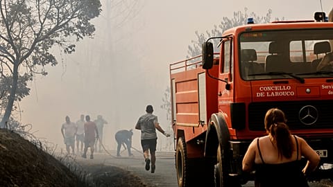 Firefighters and a local residents try to put out a forest fire in Larouco, northwestern Spain, Wednesday, Aug. 13, 2025. 