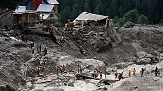یک روز پس از سیل ناگهانی در روستای چوسیتی، کشمیر تحت کنترل هند، جمعه، ۱۵ آگوست ۲۰۲۵، به زائران سرگردان با استفاده از یک پل موقت کمک می‌شود تا از آب عبور کنند