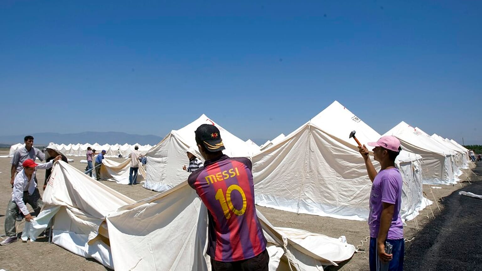  عمال الهلال الأحمر التركي ينصبون الخيام في مخيم جديد للاجئين السوريين المحتملين في بلدة أبايدين التركية في محافظة هاتاي، تركيا، الجمعة 24 يونيو/حزيران 2011.