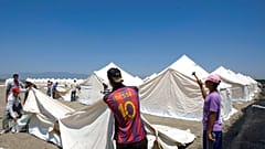  عمال الهلال الأحمر التركي ينصبون الخيام في مخيم جديد للاجئين السوريين المحتملين في بلدة أبايدين التركية في محافظة هاتاي، تركيا، الجمعة 24 يونيو/حزيران 2011.