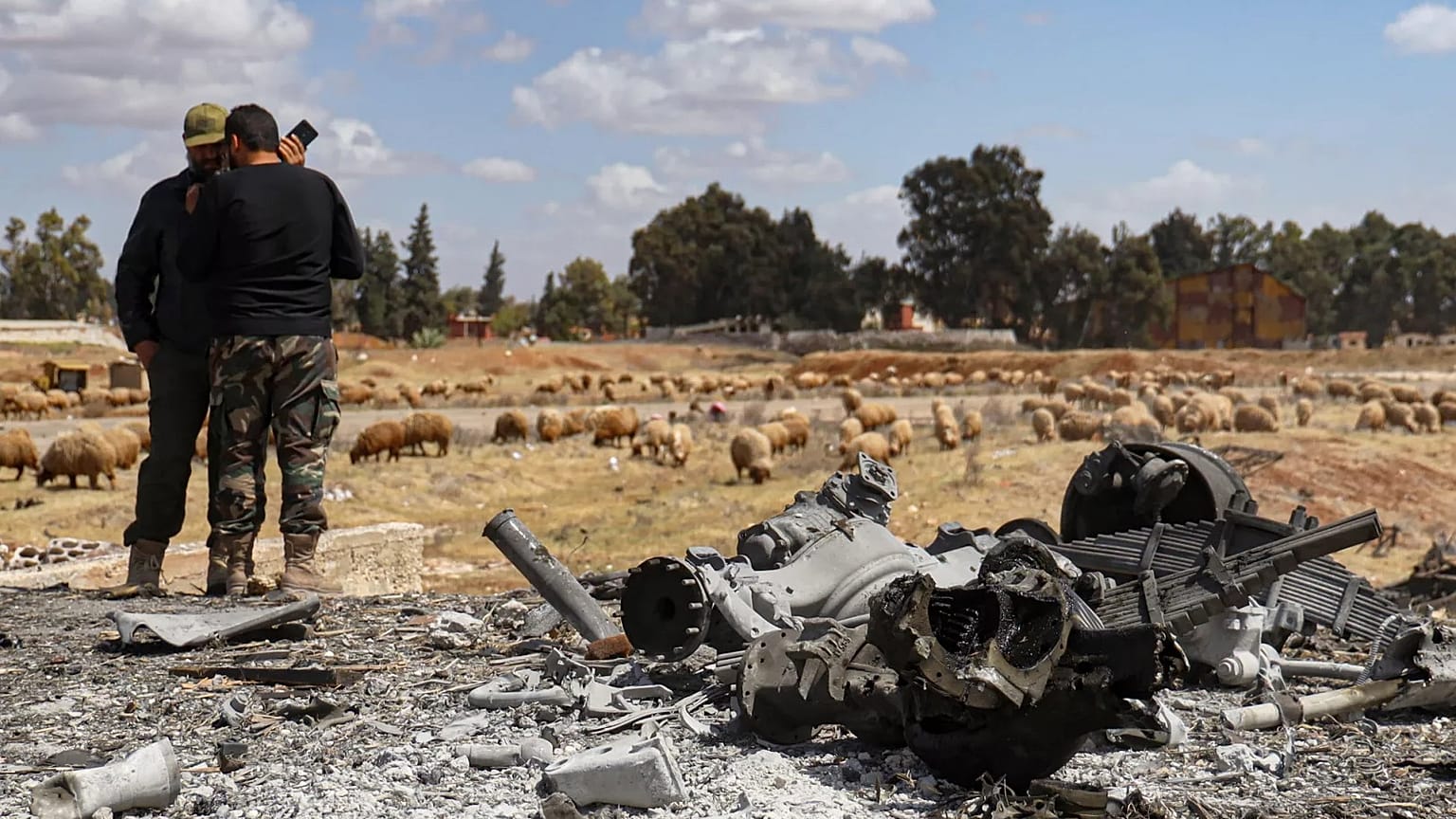 Two Syrian army officers inspect the site of an Israeli strike at a military airbase near Hama, 3 April, 2025