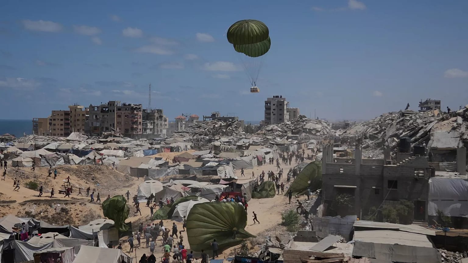 Varios palestinos corren para alcanzar la ayuda humanitaria lanzada por aire en la Ciudad de Gaza, el 7 de agosto de 2025.