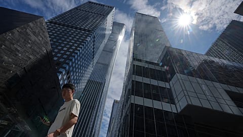 A man walks by the capital city tallest skyscraper China Zun Tower and office buildings at the central business district during lunch break hour in Beijing