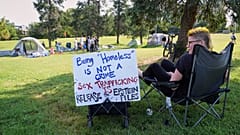 Demonstrantin Karen Irwin sitzt in der Nähe eines Zeltlagers, in dem obdachlose Menschen leben, am Donnerstag, den 14. August 2025 in Washington.
