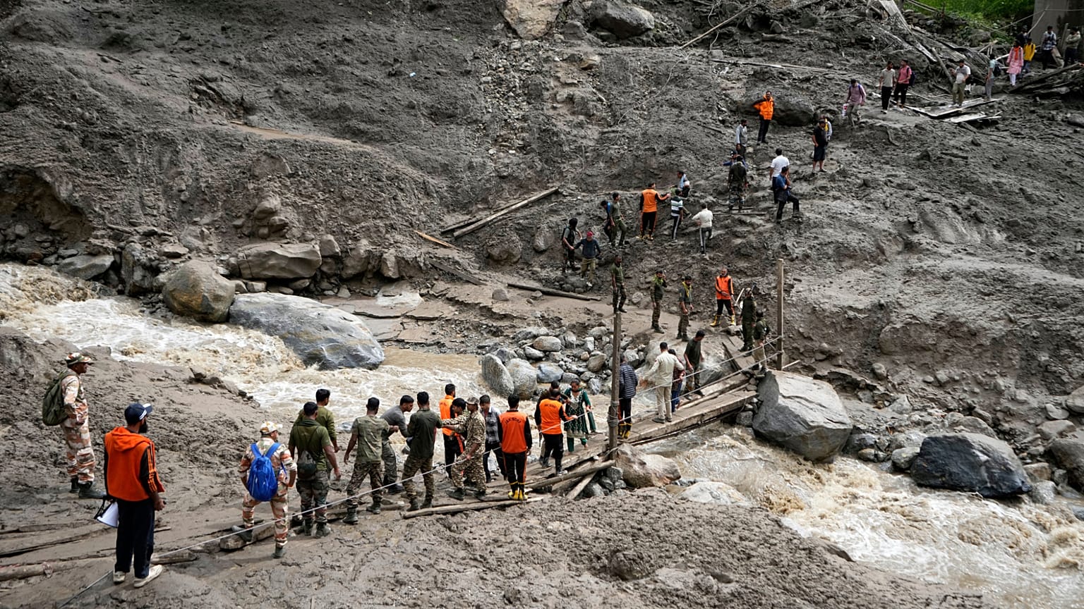 Les pèlerins bloqués sont aidés à traverser un canal d'eau à l'aide d'un pont de fortune un jour après les crues subites dans le village de Chositi, Kishtwar, Cachemire sous contrôle indien, le 15.08.2025