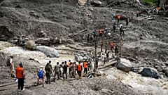 Gestrandete Pilger werden einen Tag nach den Sturzfluten im Dorf Chositi, Kishtwar, im indisch kontrollierten Kaschmir, am 15.08.2025 mithilfe einer provisorischen Brücke über einen Wasserkanal gebracht.