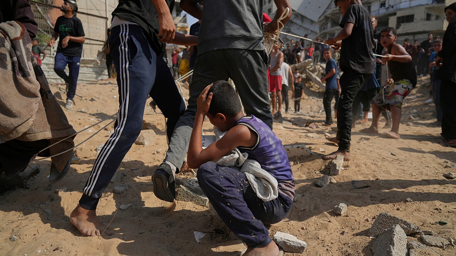 طفل فلسطيني ينحني بعد تعرضه لضربة على رأسه بينما يهرع الناس لجمع المساعدات الإنسانية التي أسقطتها المظلات على مدينة غزة، شمال قطاع غزة، الخميس 14 أغسطس/آب 2025.