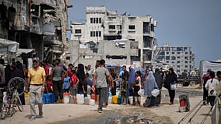 FILE: In the summer heat, Palestinians line up to collect water from a distribution point in Gaza City, 12 August 2025