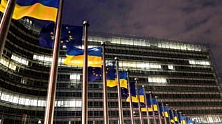 Flagi Unii Europejskiej i Ukrainy powiewają na wietrze z okazji trzeciej rocznicy pełnoskalowej inwazji Rosji na Ukrainę przed siedzibą UE w Brukseli.