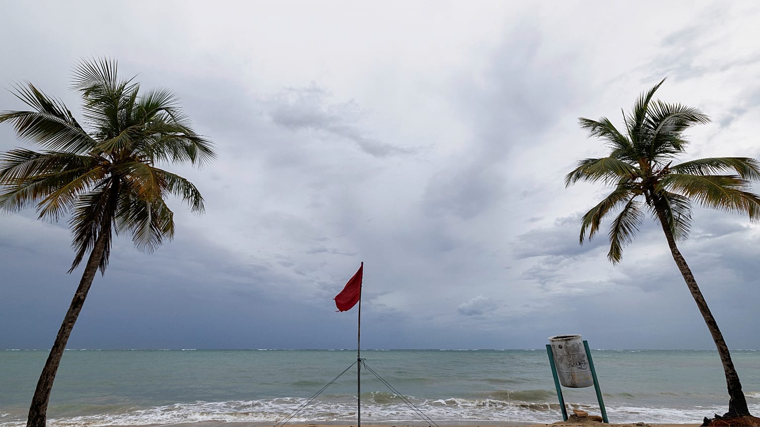 Vörös zászló figyelmeztet a veszély Puerto Rico egyik kiürül strandján, miután az Erin hurrikán elhaladt a sziget közelében 2025. augusztus 17-én