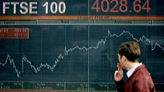 A pedestrian walks in front of a display showing the performance of Britain's FTSE 100 share index in London. October 2008.