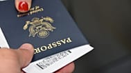 A person handing over a US passport at an EU border control airport counter