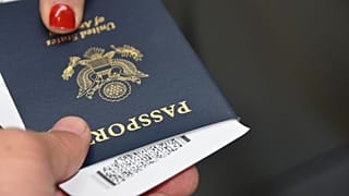 A person handing over a US passport at an EU border control airport counter