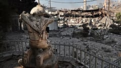 Cumartesi gecesi Lübnan'ın güneyinde İsrail hava saldırılarıyla vurulan ticari bir caddedeki Hizbullah savaşçısı heykelinin önünde yıkılmış dükkanlar görülüyor, 13 Ekim, 2024