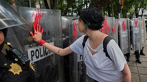 Демонстрант наносит краску на щит полицейского во время протеста против войны в Газе, Мехико, воскресенье, 17 августа 2025 года