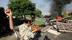 Un colono judío se prepara para lanzar una bombilla llena de pintura naranja a la policía israelí, a su llegada al asentamiento judío de Gadid, el 19 de agosto de 2005.