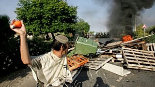 Un colono judío se prepara para lanzar una bombilla llena de pintura naranja a la policía israelí, a su llegada al asentamiento judío de Gadid, el 19 de agosto de 2005.