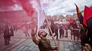 A man holds color smoke during the farewell ceremony of David Chichkan, a Ukrainian serviceman and artist at Independence square in Kyiv, Ukraine, on Monday, Aug. 18, 2025.