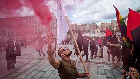 Мужчина держит цветной дым во время церемонии прощания с Давидом Чичканом, украинским военнослужащим и художником, на площади Независимости в Киеве, Украина, в понедельник, 18 августа 2025 года.