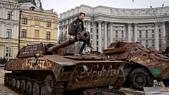 Ein Junge sitzt auf einem ausgestellten beschädigten russischen Panzer im Zentrum von Kiew, Ukraine. März 2025.