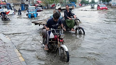 Motorcyclists navigate through a flooded road after heavy rainfall in Karachi, 19 August, 2025