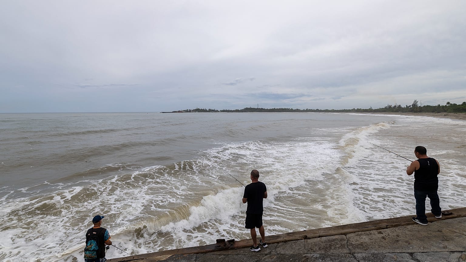 Des personnes pêchent le long du rivage à Arecibo, Porto Rico, alors que l'ouragan Erin provoque des pluies sur l'île.