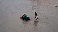 People navigate through a flooded road after heavy rainfall in Karachi, Pakistan, Tuesday, Aug. 19, 2025.