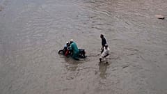 Menschen bewegen sich auf einer überfluteten Straße nach starkem Regen in Karatschi, Pakistan, Dienstag, 19. August 2025.