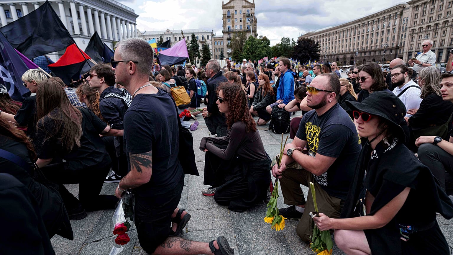 Des personnes se tiennent à genoux lors de la cérémonie d'adieu de David Chichkan, un militaire et artiste ukrainien, sur la place de l'Indépendance à Kiev, en Ukraine, le lundi 18 août 2025.