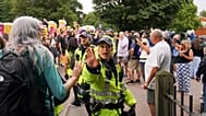A police officer reacts as demonstrators hold placards and banners as they leave a protest outside the Bell Hotel in Epping, 27 July, 2025