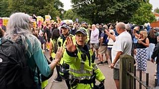 A police officer reacts as demonstrators hold placards and banners as they leave a protest outside the Bell Hotel in Epping, 27 July, 2025