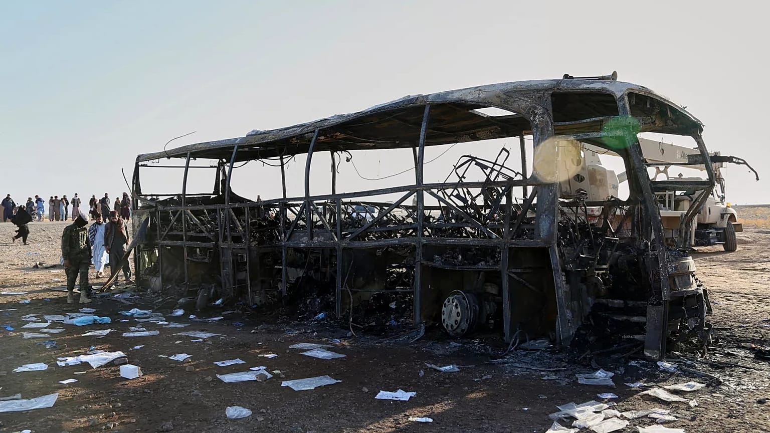 People and soldiers from the Taliban army inspect a burned-out bus that collided with a truck and a motorbike in Herat province, 20 August, 2025