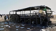 People and soldiers from the Taliban army inspect a burned-out bus that collided with a truck and a motorbike in Herat province, 20 August, 2025