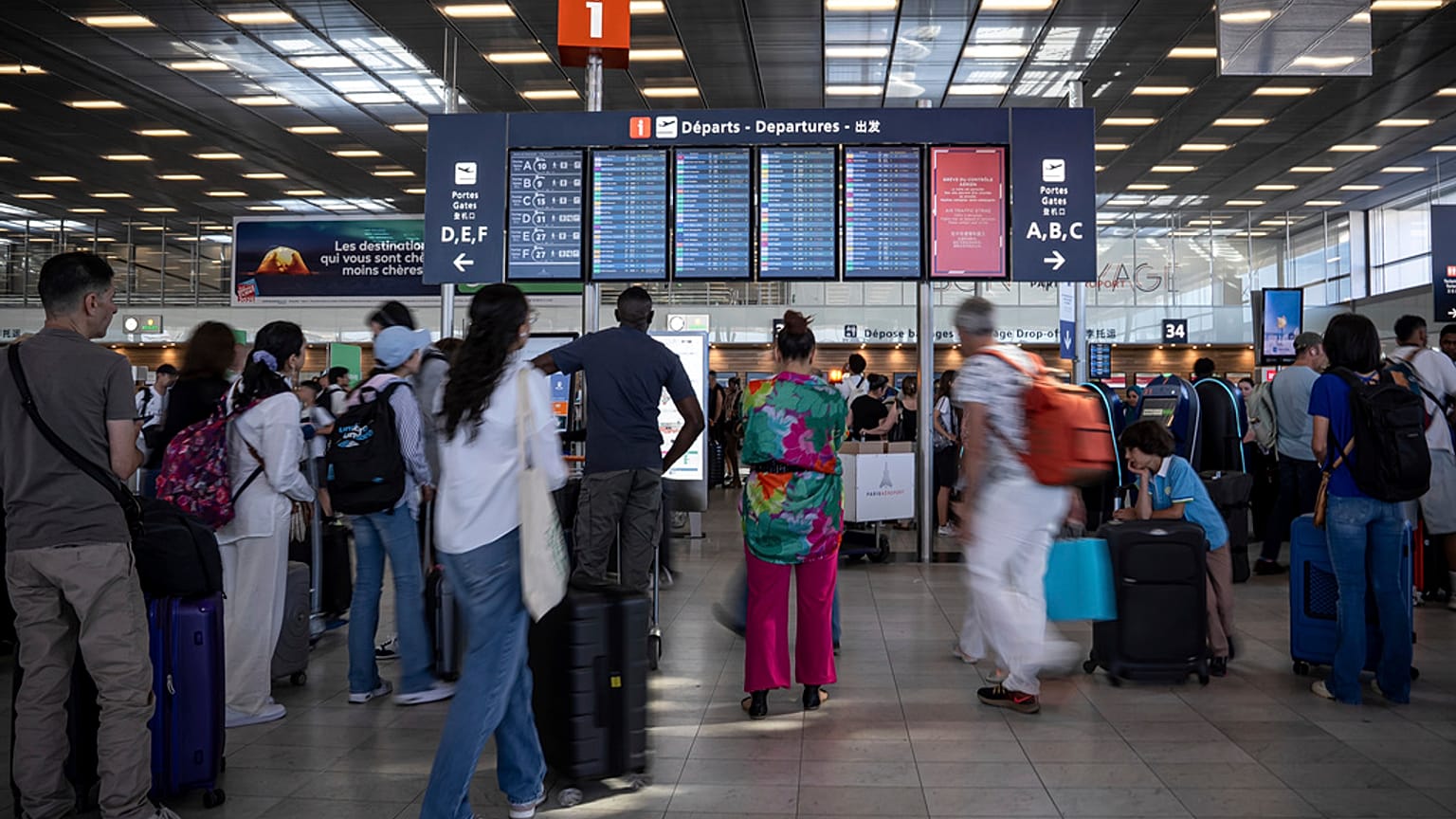 Des passagers regardent un panneau d'information sur les départs à l'aéroport d'Orly, près de Paris.