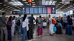 Passagiere schauen auf eine Informationstafel für Abflüge am Flughafen Orly in der Nähe von Paris.