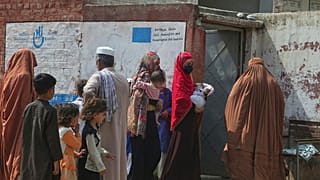 لاجئات أفغانيات يدخلن مركزًا صحيًا في مخيم كابابايان للاجئين في بيشاور، باكستان، في 8 أبريل 2025
