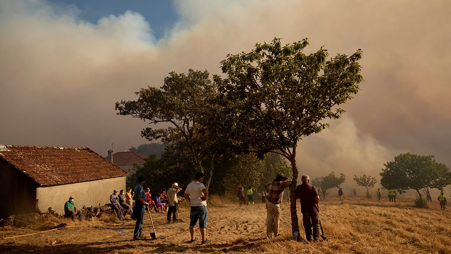 Residents and firefighters battle a wildfire advancing toward Rebordondo village, near Ourense, in northwestern Spain, on Monday, Aug. 18, 2025.