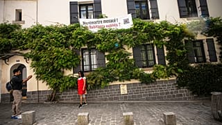 A banner reading "Montmartre under threat. Are residents being forgotten?" hangs at windows in the Montmartre district in Paris, France.