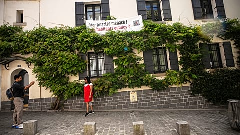 A banner reading "Montmartre under threat. Are residents being forgotten?" hangs at windows in the Montmartre district in Paris, France.