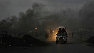 فلسطينيون يقودون سياراتهم وسط دخان أسود من مواقد مؤقتة تستخدم لاستخراج الوقود من البلاستيك المذاب على طول طريق البحر، عند الغسق في جنوب مدينة غزة