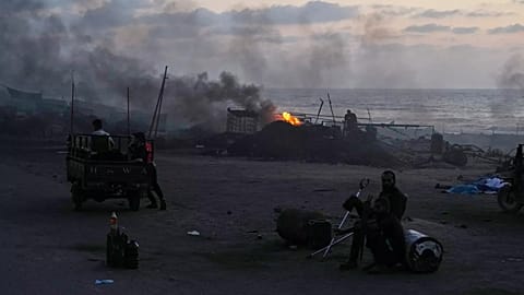 Menschen sitzen neben behelfsmäßigen Verbrennungsanlagen entlang der Sea Road im Süden von Gaza-Stadt, 21. August 2025