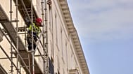 A construction worker stand on a scaffold in Madrid, Spain, Tuesday, Aug. 12, 2025