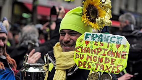 A yellow vest protestor holds a sign reading "France is the world champion of taxes" during a march in Paris. 4 May 2019.