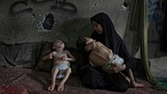 سماح مطر تقف لالتقاط صورة مع ابنيها ، يوسف ، 6 سنوات ، بين ذراعيها ، وأمير ، 4 سنوات ، متأثرين بسوء التغذية والشلل الدماغي ، في مدرسة تديرها الأمم المتحدة في مدينة غزة 