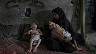 سماح مطر تقف لالتقاط صورة مع ابنيها ، يوسف ، 6 سنوات ، بين ذراعيها ، وأمير ، 4 سنوات ، متأثرين بسوء التغذية والشلل الدماغي ، في مدرسة تديرها الأمم المتحدة في مدينة غزة 