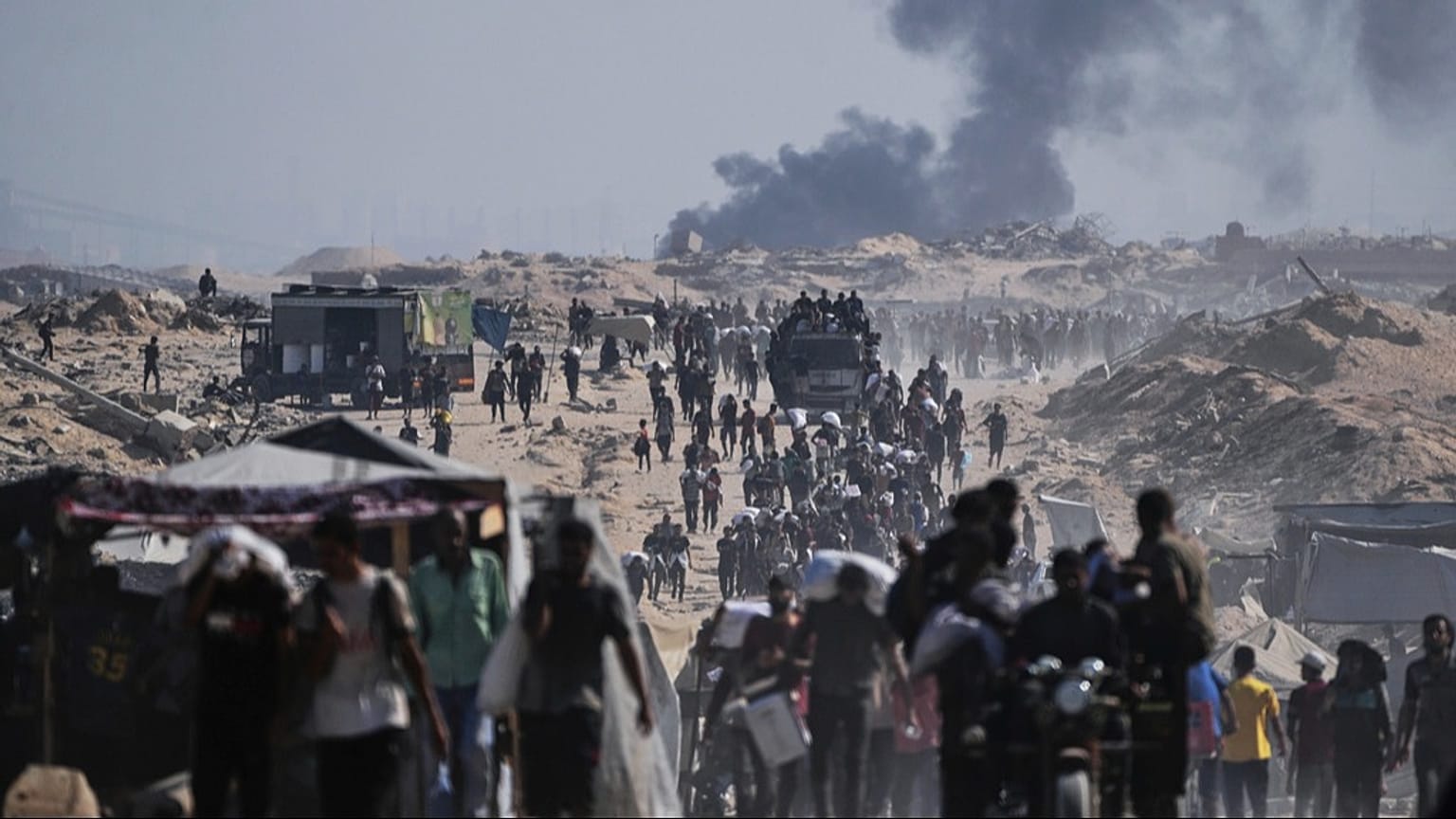 Palestinians carry sacks of flour unloaded from a humanitarian aid convoy on the outskirts of Beit Lahiya, northern Gaza Strip, Saturday, Aug, 23, 2025