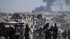 Palestinians carry sacks of flour unloaded from a humanitarian aid convoy on the outskirts of Beit Lahiya, northern Gaza Strip, Saturday, Aug, 23, 2025